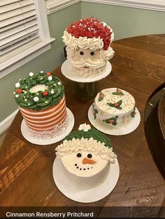 four decorated cakes sitting on top of a wooden table