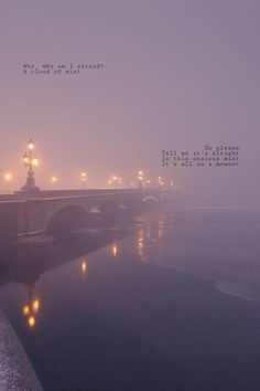 a foggy river with a bridge and street lights