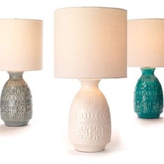 three different colored lamps sitting next to each other on a white surface with one lamp turned off