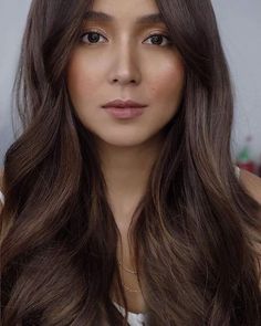 a woman with long brown hair is looking at the camera