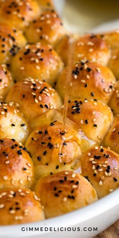 a white bowl filled with rolls covered in sesame seeds