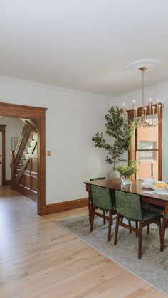 a dining room table with green chairs and a chandelier