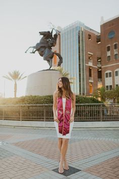 a woman standing in front of a statue with her hand on her hip and looking up at the sky