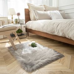 a bedroom with a bed, chair and white fur rugs on the wooden floor