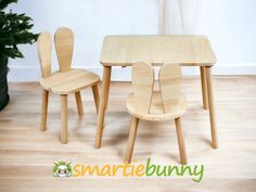 a wooden table and two chairs sitting on top of a hard wood floor next to a potted plant