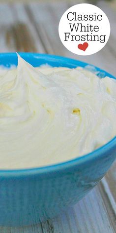 a blue bowl filled with white frosting on top of a wooden table