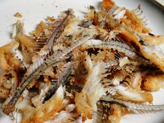 some dead fish on a white plate with brown and black flecks in it