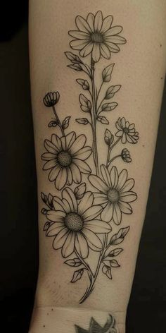 a black and white tattoo with flowers on the side of a woman's arm