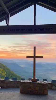 a wooden cross on top of a stone wall under a sign that says, will lift my eyes to the hills