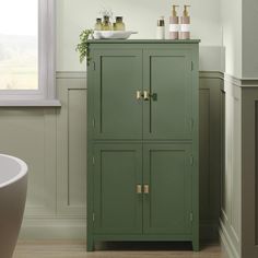 a green cabinet in a bathroom next to a tub