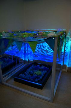 an aquarium with rocks under it and blue lights in the water behind it on display