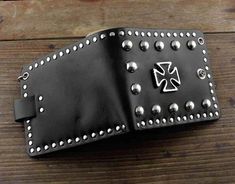 a black leather wallet with silver studs on the front and sides, sitting on a wooden surface