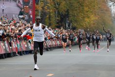 a group of men running down a street next to a crowd