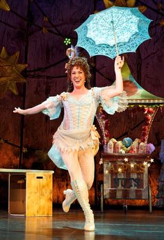 a woman is dancing on stage with an umbrella