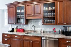 a kitchen with wooden cabinets and granite counter tops, stainless steel dishwasher and sink