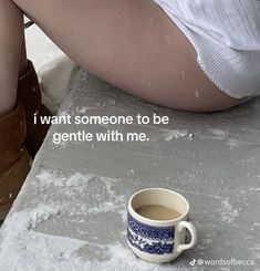 a cup of coffee sitting on top of a table next to a woman's legs