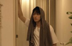 a woman with a towel on her head is standing in front of a door and looking at the mirror