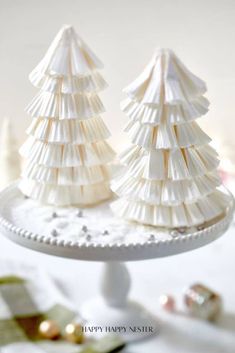 two small white christmas trees sitting on top of a cake plate next to each other