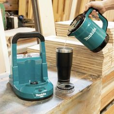 a person pouring something into a glass on top of a wooden table next to stacks of wood