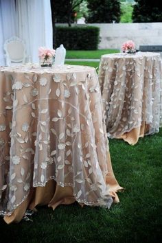 two tables covered with tablecloths and flowers on top of them in the grass