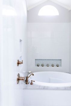 a white bath tub sitting inside of a bathroom next to a shower head and faucet