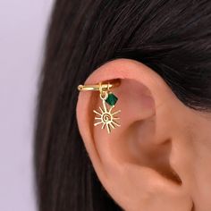 a woman's ear with a small green stone in the shape of a sun