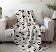 a white couch with a black and brown dog paw print blanket on top of it