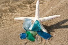 a starfish on the sand with several pieces of sea glass in it's shell