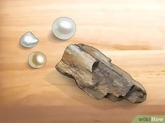 a rock and three pearls on a wooden surface