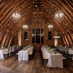 the inside of a barn with tables and chandeliers