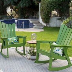 two green rocking chairs sitting on top of a patio next to a swimming pool in the back yard