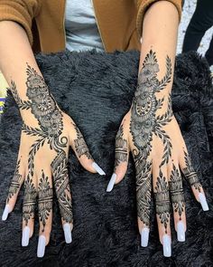 a woman's hands with henna tattoos on them