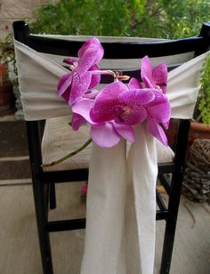 purple orchids sit on the back of a chair