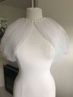 a mannequin wearing a white dress with pearls on it