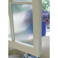 a window with frosted glass on it and a blue potted plant in the background