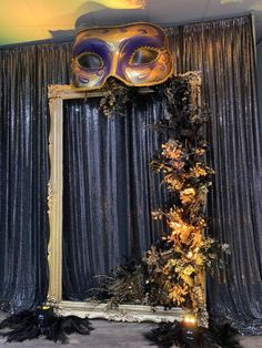 a mardi gras mask on top of a mirror with black feathers around it