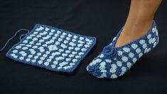 a close up of a person's feet wearing crocheted slippers next to a blue and white square