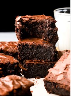 chocolate brownies stacked on top of each other with a glass of milk in the background