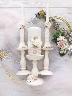 a white candle holder sitting on top of a table next to flowers and other items