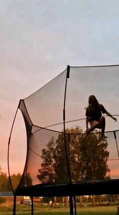 a person on a trampoline with trees in the back ground and sky behind them