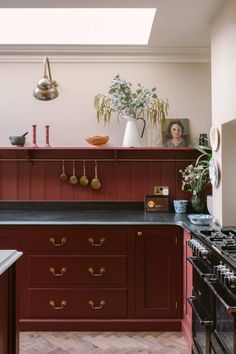 a kitchen with red cabinets and black counter tops, pots on the stove top and potted plants in vases