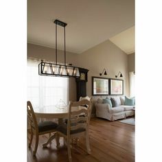 a dining room table and chairs in front of a living room with wood flooring