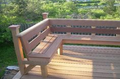 a wooden bench sitting on top of a wooden deck next to a lush green hillside