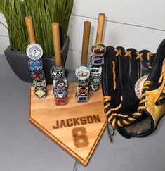 a baseball mitt, glove and ball markers on a wooden base with grass in the background