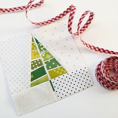 a christmas tree is on the side of a piece of fabric next to a spool of red and white twine