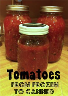 three jars filled with tomato sauce sitting on top of a wooden table