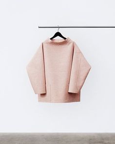 a pink sweater hanging on a clothes line in front of a t - shirt hanger