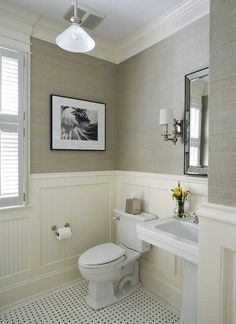 a white toilet sitting next to a sink in a bathroom under a window with shutters