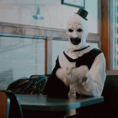 a person in a white mask sitting at a table