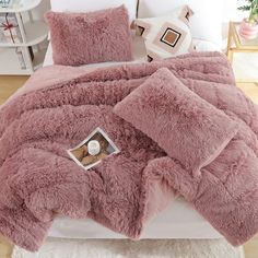 a bed covered in pink fluffy blankets and pillows